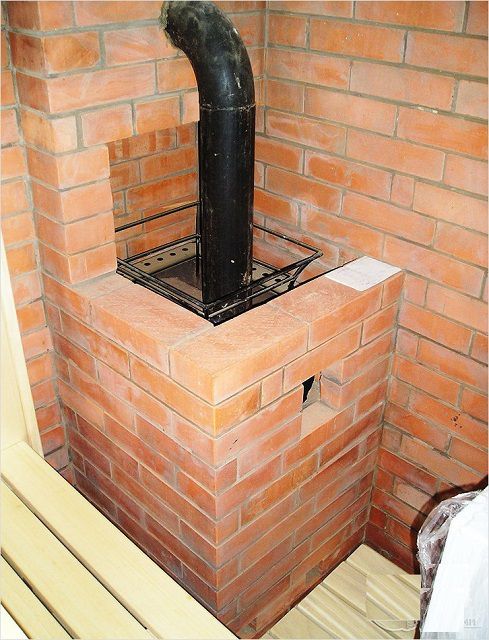 La estufa de sauna está conectada a la chimenea principal mediante un tubo de metal.