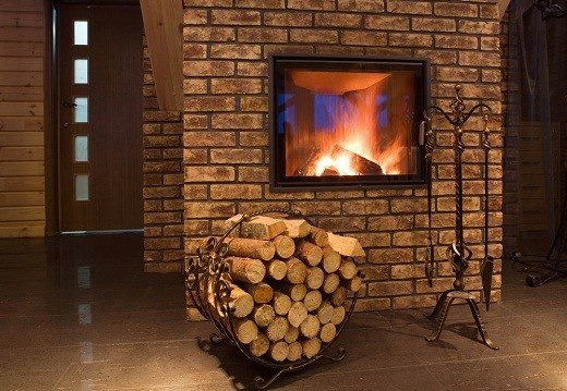L'immagine mostra un caminetto riscaldante con una posa di legna da ardere per esso